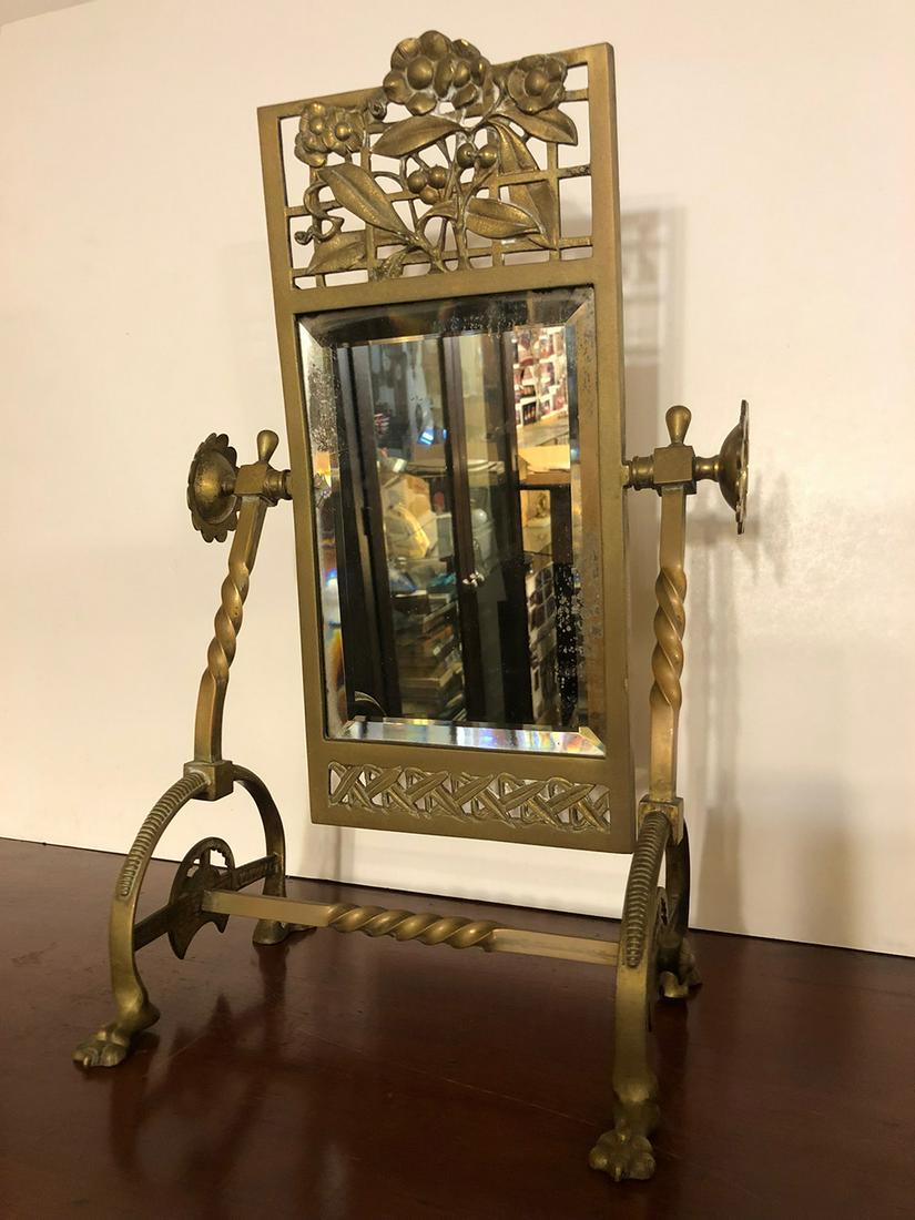 Aesthetic Period Brass Ladies Jewelry Mirror: Aesthetic Period Brass Ladies Jewelry Mirror with claw feet and unbelievable 3 dimensional berries and flowers, bevelled glass, in very unusual style.Measures approx. 9.25” wide x 17” tall