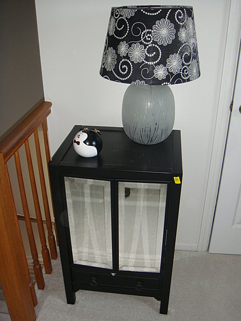 2 Door Mirrored Black Lacquer Stand with Lamp and: 2 Door Mirrored Black Lacquer Stand with 1 Drawer Base with etched cut table lamp and small bird porcelain bank plus 2 shelves with contents, including estate contents of videos, candles, decorative e