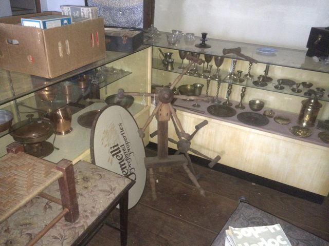 Treasure Trove Lot: Treasure trove including a collection of vintage brass and vintage copper items, vintage paper, sailing ship, rugs and quilt racks, prints, drum set, glassware, drop leaf table, and many other items