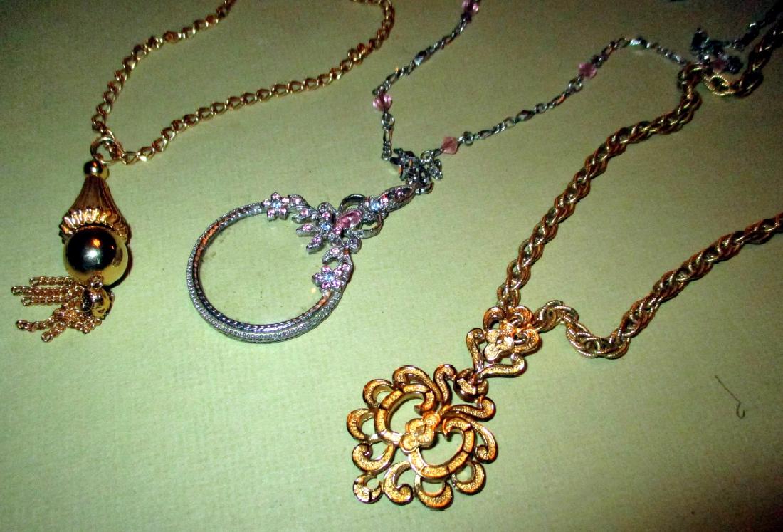 Three Vintage Costume Jewelry Pendants: Three costume jewelry pendants with chains. One is a jeweled silver tone monocle set with colored rhinestones, one is signed Trifari and the other is unsigned. Circa 1950/60s. All in good condition.