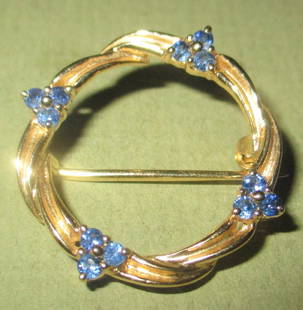 14K Yellow Gold & Sapphire Circle Pin: 14K circle pin with a roped gold design set with three sapphire clover leaf clusters. In good condition. Measures 1" in in diameter.