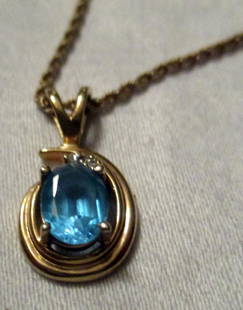 Blue Topaz on a 14K Gold Rope Chain: Blue topaz set in a 14K yellow gold setting. Hangs from a 14K gold rope chain. The chain has two areas where a link is broken but not apart. Pendant is in good condition.