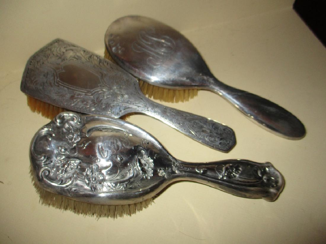 Three Sterling Hair Brushes: Lot of three sterling hairbrushes. One is Art Nouveau design, one is Edwardian design and the last is plain with some minor denting. The other two are in good condition.