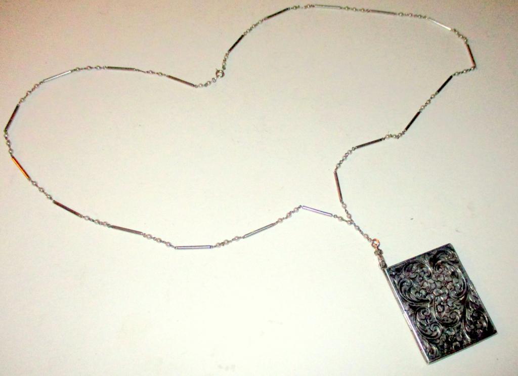 Silver Edwardian Locket & Chain: Lot consisting of a silver locket with hand chased work that hangs from a silver chain with three sea pearls between each link. However, two of the pearls are missing between two links. It is almost u