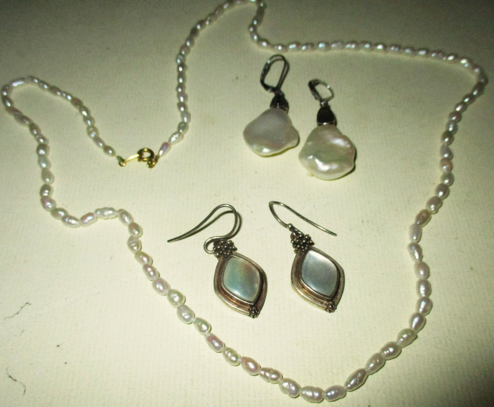 Lot of Pearls and Mother of Pearl Jewelry: This lot consists of a fresh water pearl necklace with a 14k gold clasp and two pair of sterling silver earrings set with mother of pearl, All are in good condition, The size of the necklace is approx