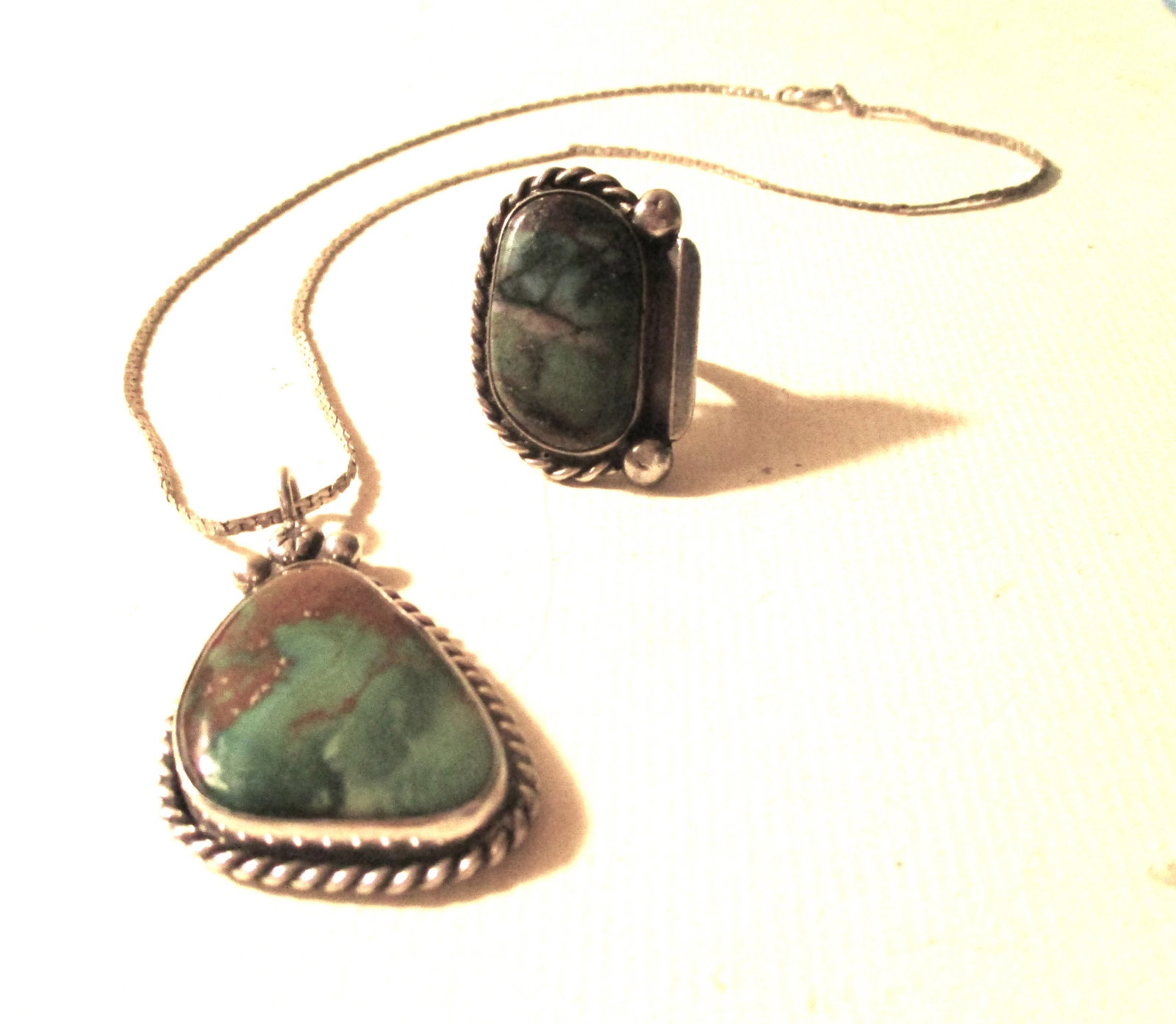 Two Piece Set of Navajo Jewelry: This lot consists of a set of Navajo Jewelry. One is a sterling Navajo ring set with turquoise with approx. size #6 and a pendant set in sterling silver on a sterling chain, The turquoise stone are th