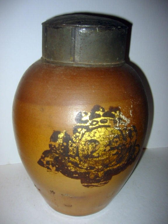 18/19th Century Tobacco Crock/Jar: 18/19th century salt glazed tobacco jar with a tole cover. There is a gilt emblem on front, #24. 12" tall and in good condition.