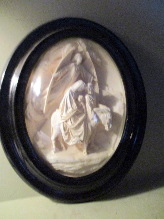 Plaster Relief of Holy Family Flight from Egypt: Plaster relief of the Holy Family fleeing from Egypt in an oval frame with a bubble glass over it. Lot is in good condition.
