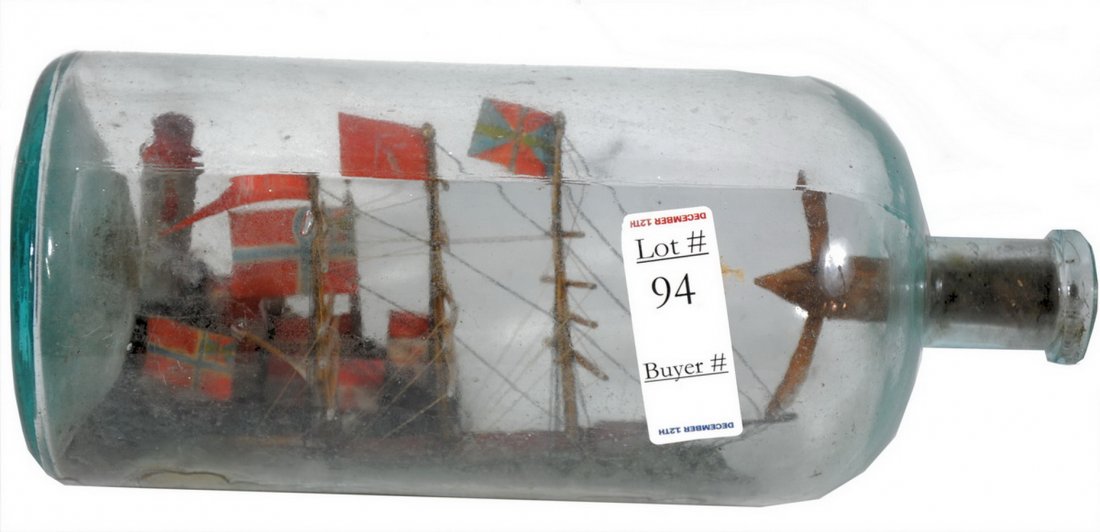 Handmade ship in a bottle 12": Handmade ship in a bottle 12" with British flags flying and small village with houses and makeshift lighthouse behind.