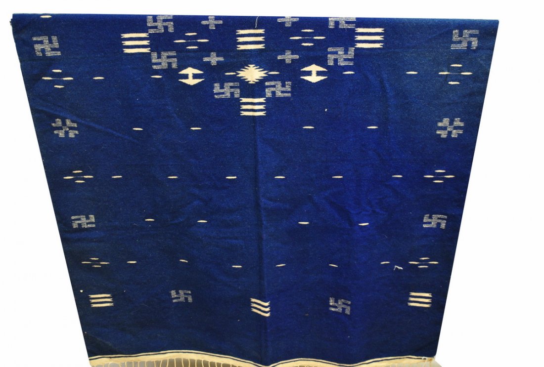 Native or Central American Rug: This 71 X 43.5" woven wool rug has a deep navy blue background with cream colored symbols, predominantly a swastika-like symbol, which represents a "Whirling Log" in Native American symbolism; in Pana