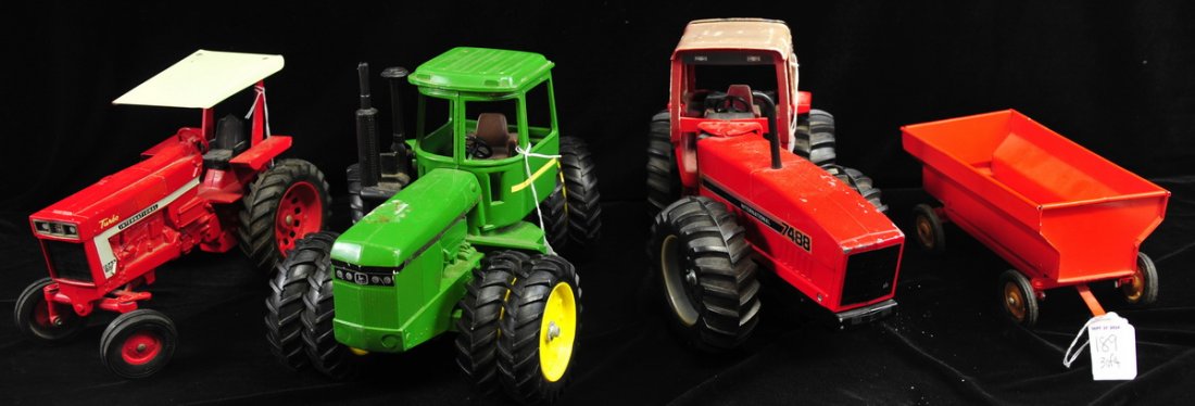 Four tractor toy collection: International Farmall 1066, John Deere, International 7488 and a tin trailer painted orange.