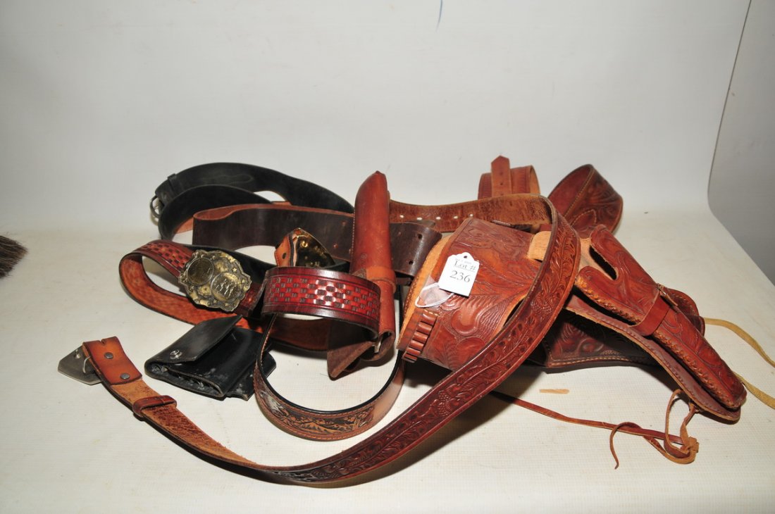 Collection of leather holsters and belts: including a decorated belt with American bald eagles and buckle made by Dixie Leather. Decorated leather belt with acorns and leaves, some with patterns and decorations. "Hunter" leather holster with 