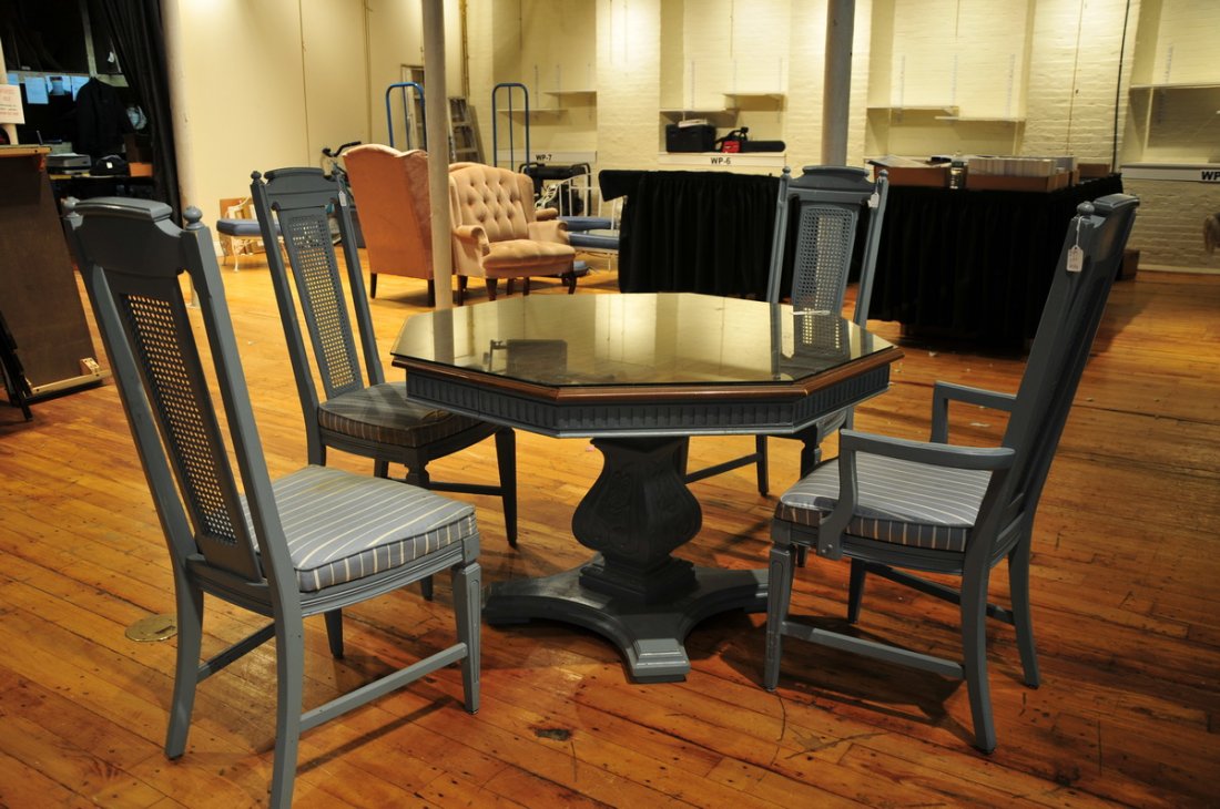 Round blue wooden table with four chairs: manufactured by the Stanley Furniture Co, VA. Three side chairs and one arm chair, caned backs with blue seat cushions ( has some ripping) and wood construction. Octagon table top with base, has one l