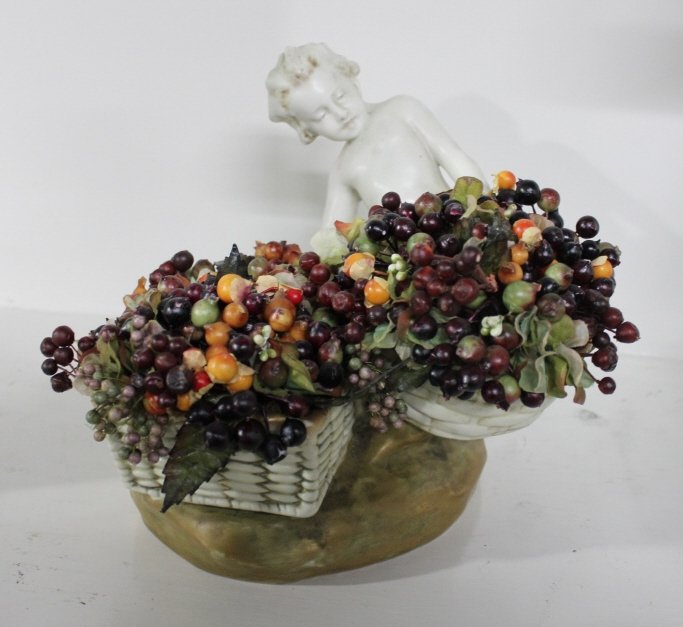 Antique Austrian Amphora Porcelain Statue: Cherub with fruit basket. Incised with the makers mark on the interior. Height 9 inches. Width 11 inches. Depth 6 inches. Property of a Bedford Hills NY Home.