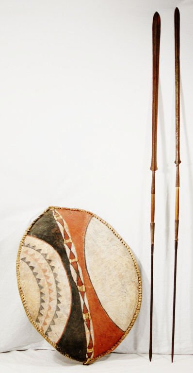 African Tribal Shield with Two Swords: Painted geometric pattern in red, white, and black on front. Length 33 Inches Width 27 Inches
