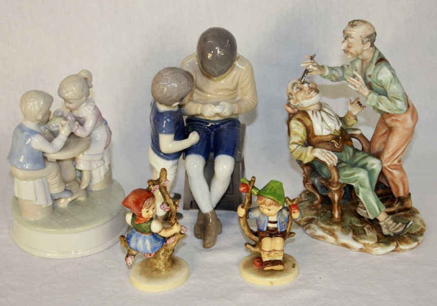 Group of Porcelain Figurines: Two little boys marked Kjobenhavn, figurine of young boy and girl eating ice cream, two Hummel figurines, and barbershop scene figurine tallest height 9 Inches
