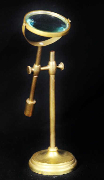 Antique Brass Magnifying Glass: On adjustable stand. Height approximately 12 Inches Diameter of base 4 Inches.