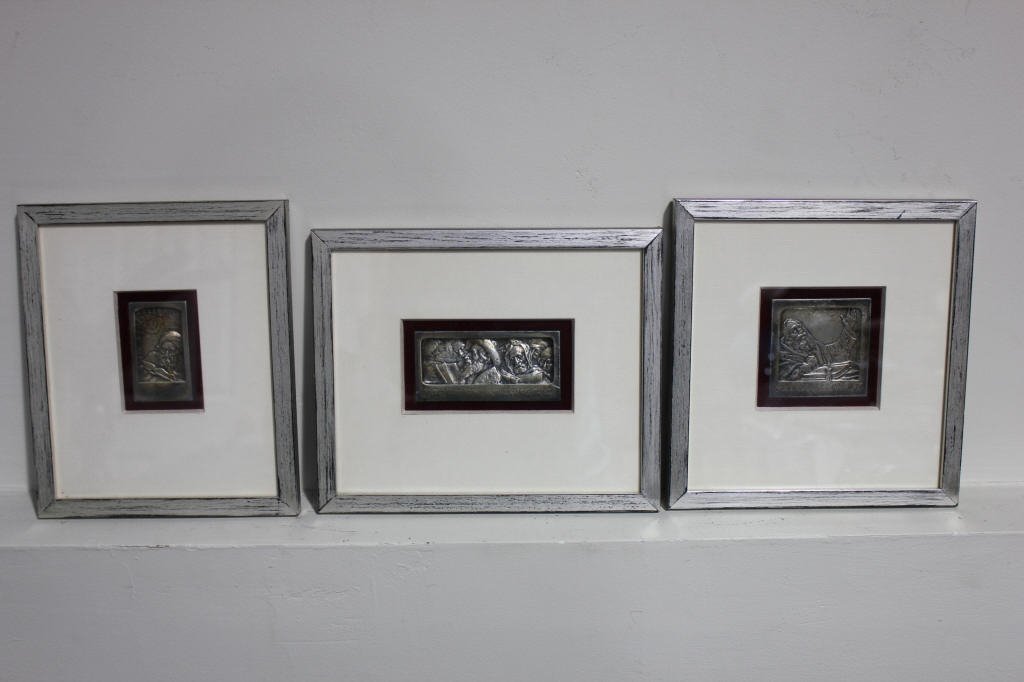 Trio of Framed Judaic Silver Sculptures: Three sculptures of rabbinical scenes on silver with Hebraic engraving. Height x Width: rabbi reaching upwards: 2.8 inches x 2.8 inches, turban clad rabbi with book: 2.6 inches x 1.5 inches, Jews in p