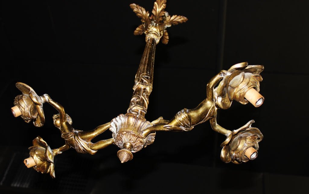 Antique Bronze Two-Arm Four Light Chandelier: Cherubs holding two roses each rose holding light Pineapple Finial Height 18 Inches Width Width 20 Inches