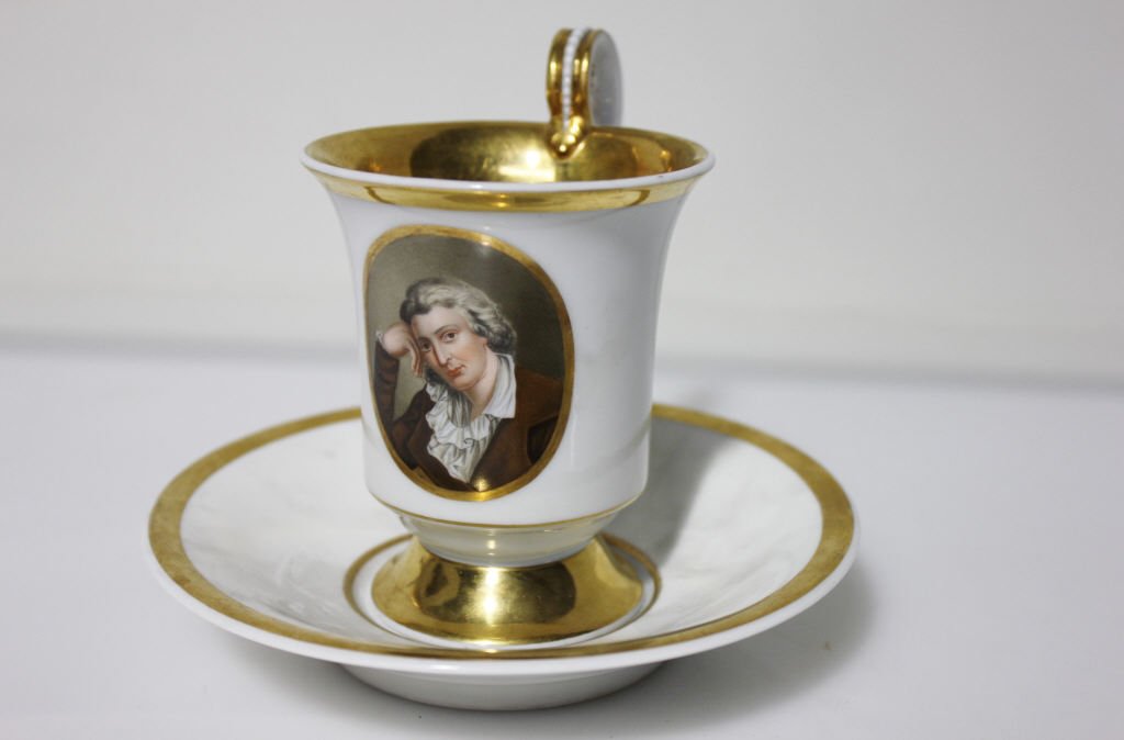 Gilted White KPM German Cup & Saucer: Featuring portrait of a woman. Cup height: 4.75 inches. Diameter: 3 inches. Plate height: 1.25 inches. Diameter: 5.75 inches.