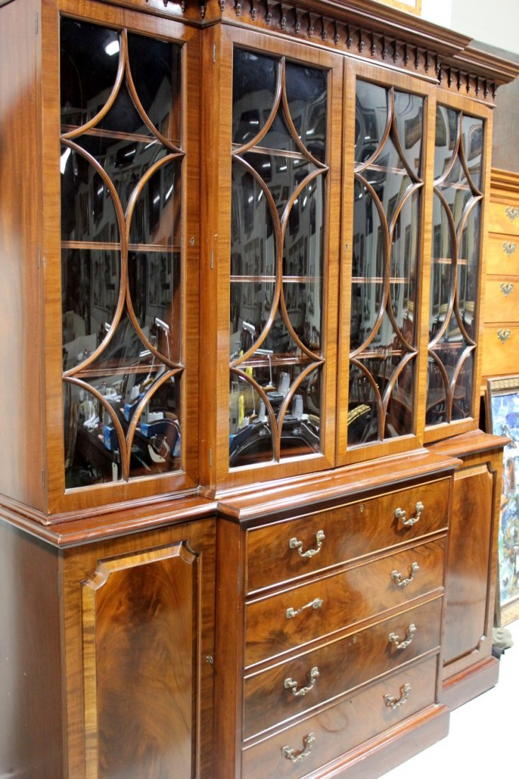 Hille of London Mahogany Breakfront: Featuring Gothic cornice, curved glass panes, leather-top fold-down desk. Height: 80 inches. Width: 64.5 inches. Depth at deepest point (center): 18 inches. Condition: Very good with normal wear for i