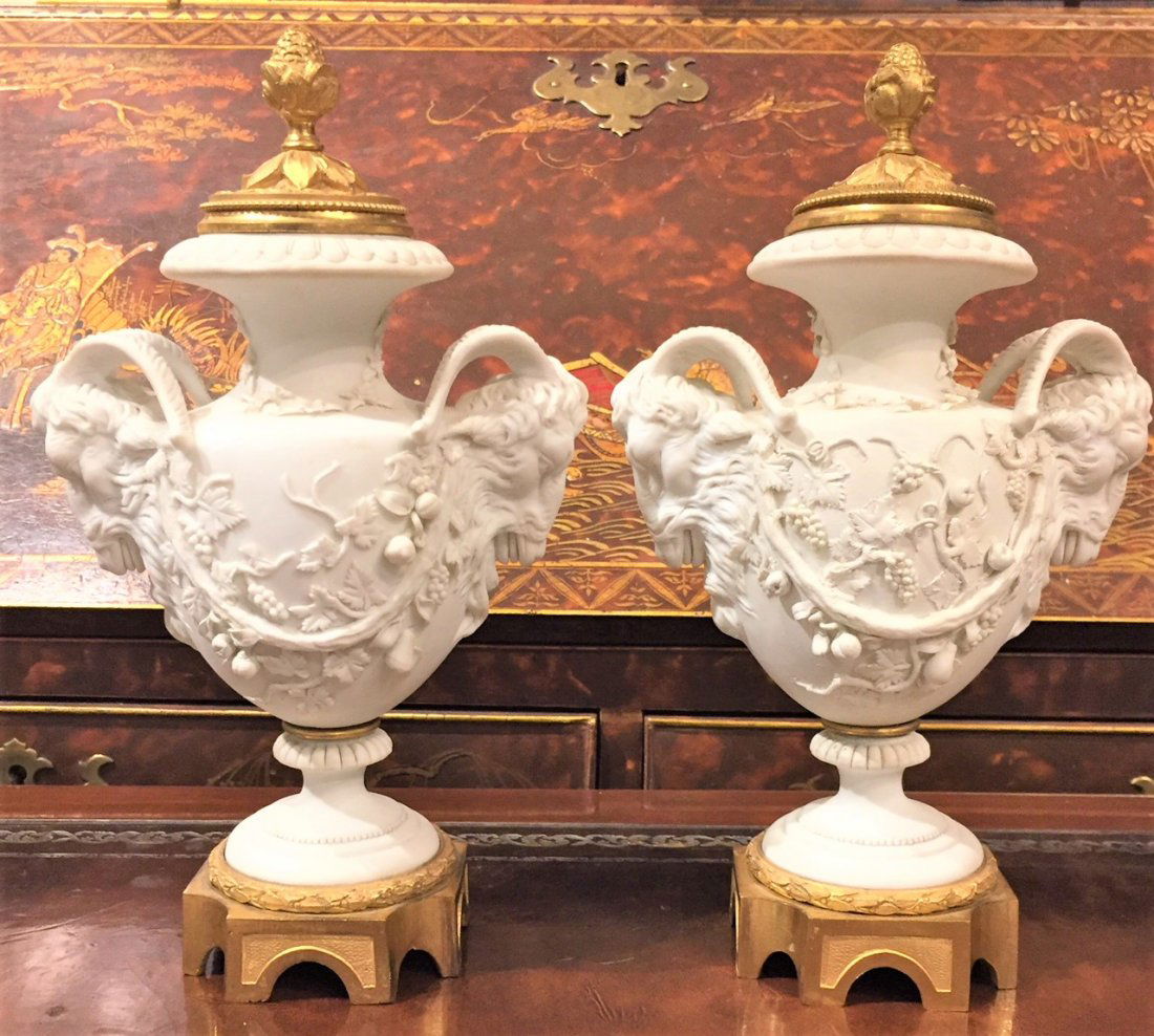 Pair Of French Bisque Urns: Bisque Urns With Rams Heads Handles On Gilt Metal Bases, Fine Applied Grape Clusters And Vines, Underside Shows Much Rust, Crossed L Marks With F Inside; Likely That Of The Late 19th Century Paris Sam