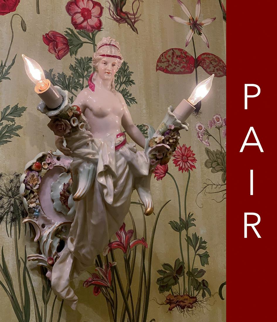 Pair Of Antique Meissen Style Porcelain Sconces: Each with Partially Clad Woman Holding Two Lights. One Has Old Repair To Arm. Loss To Several Flower Petals. Working At Time Of Photography, But Wiring Not Guaranteed. 14 X 10 X 10