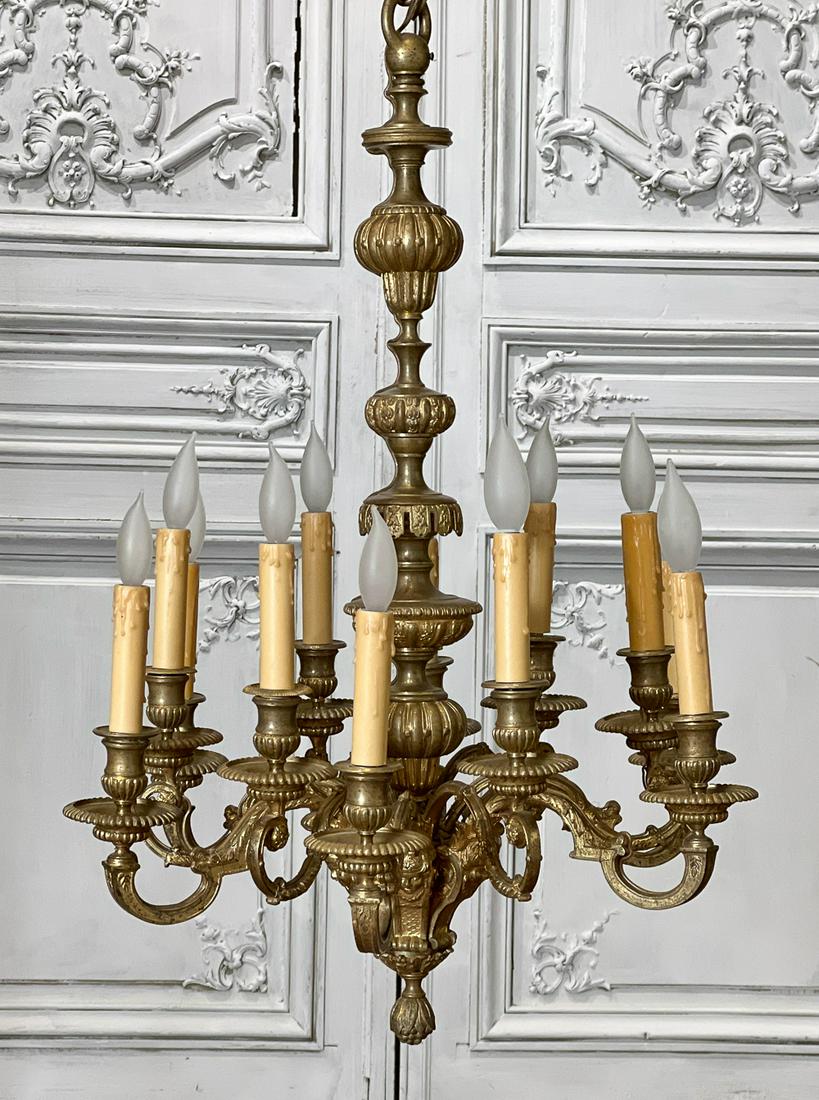 Regence Style Gilt Bronze Chandelier: 20th Century, Lobed Standard, Twelve Scroll Arms Width Elaborate Candle Cups And Bobeches, Masque Terms Above A Fruit Pendant, Height 27, Diameter 20 Inches. Electrification Present But Not Guaranteed