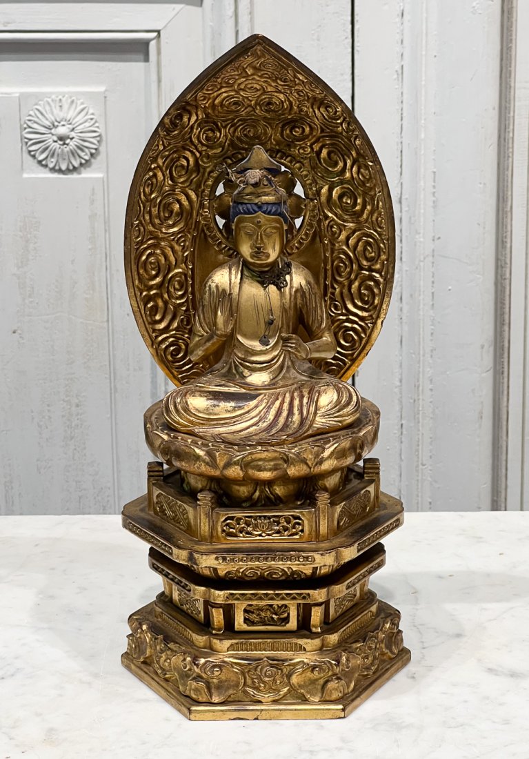 Meiji Carved Gilt Wood Buddha: Japanese, 19th Century, seated pose with mandorla behind and on a lotus, black lacquer details, height 14, width 6, depth 5 inches, retains remnants of metal adornments, attractive rubbing to gilt sur