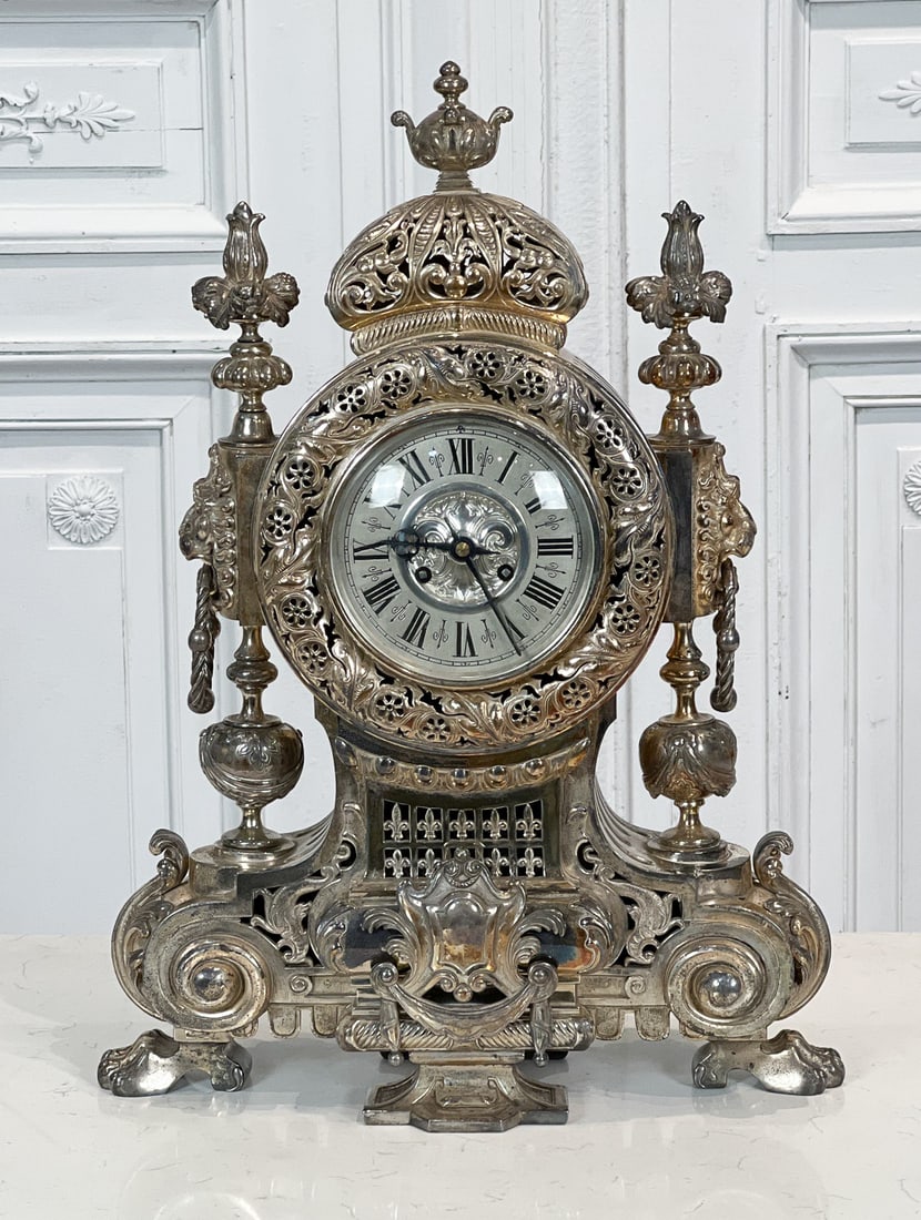 Tiffany & Co. Silvered Bronze Clock: Late 19th Century, Works Stamped Tiffany & Co. MI, 1542, Pierced Crest And Chapter Ring, Lion Masque Stiles, Volute Base, Paw Feet, Height 24, Width 14, Depth 6 Inches, Clockworks And Key Present, Fun