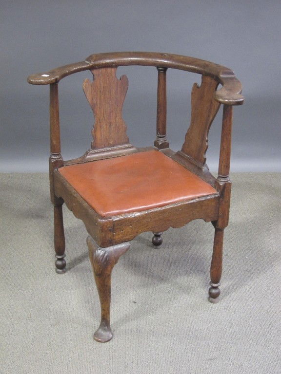 CORNER CHAIR: An 18th C. English Queen Anne dark patinated oak corner chair having twin Vasi form splats above a brown upholstered slip seat raised on curved legs, having shell carved knees, terminating on pad feet