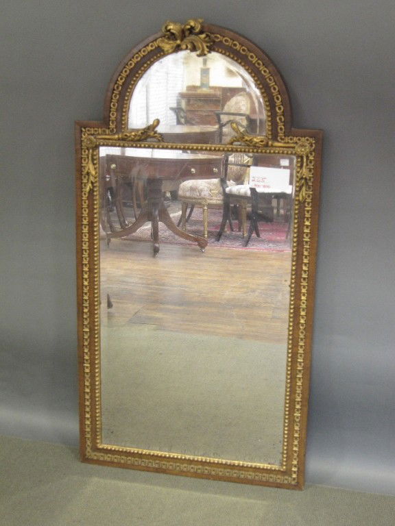 ANTIQUE MIRROR: First quarter 19th c. atrium form mahogany beveled mirror with parcel gesso and gilt decoration. The beaded molded surround applied with acanthus leaf decoration. Provenance: Edmund Franzkowiak, Berli