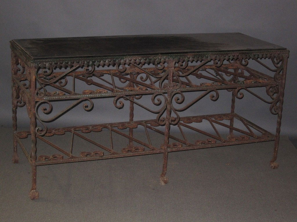 ANTIQUE RECTANGULAR WROUGHT IRON CONSOLE TABLE: Console table. A antique wrought iron. Three tier garden console table. The rectangular top above two open forming shelves having scroll work panels. The whole resting on six scrolled feet.Reportedly
