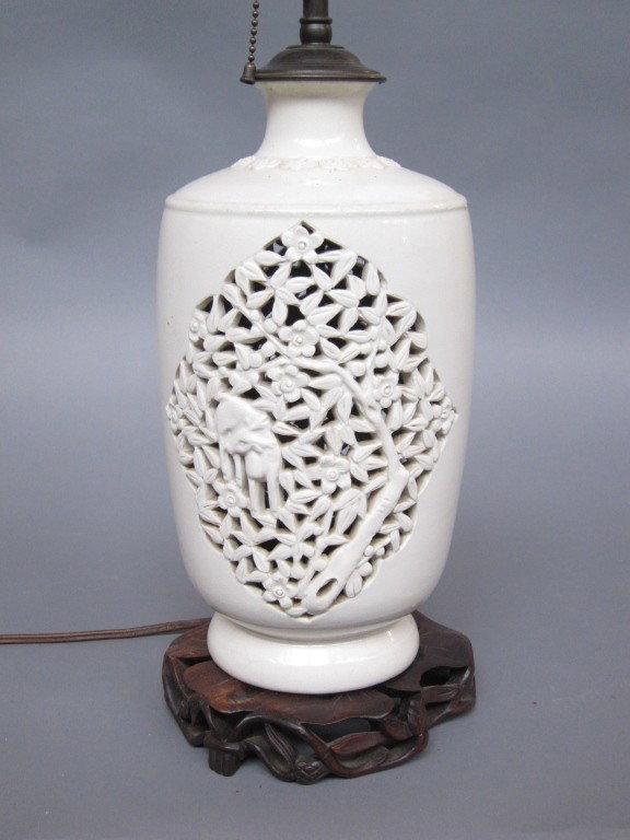 BLANC DE CHINE VASE: With pierced panels decorated with deer and flowering trees. H. 13." Mounted as a lamp on a carved wood base.