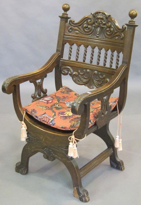 LIBRARY CHAIR: A late 19th/ early 20th C. American Renaissance revival carved oak Dante chair having a "East Wind" carved crest centered by ball finials above barley twist spindled back over a curved seat. 44.5" in