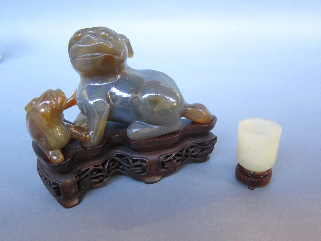TWO PIECES ORIENTALIA: Carved agate group of a foo lion and cub on a conforming carved teak base. L. 5.5." Along with a finely carved soapstone figure of Buddha, mounted on a marble base. H. 7" with base.