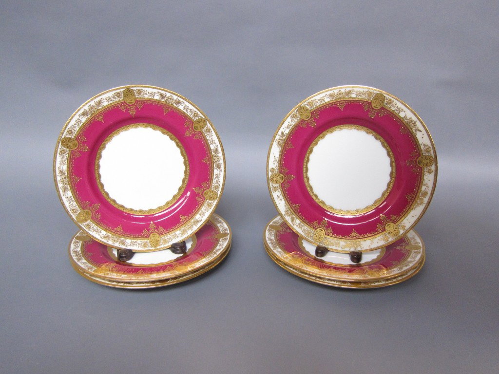 SET OF SIX ENGLISH MINTON SERVICE PLATES: Wide deep pink bands with ecru and gilt rim band with floral medallions. Diam. 10.5." Retailed by Tatman, Chicago.