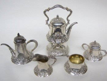 REDLICH & CO. STERLING SILVER ART NOUVEAU TEA SET: Comprised of 5 pieces, teapot on warming stand, coffee pot, sugar bowl, creamer and waste bowl. All with heavy raised floral decoration. The sugar and creamer having gold vermeil wash interiors. Teapo