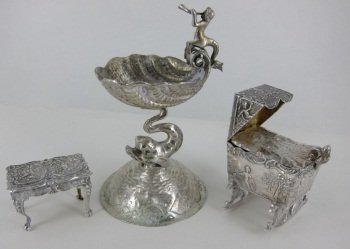 GROUP THREE MINIATURE SILVER ITEMS: A continental silver shell and dolphin master salt with a Triton on the rim (H. 4 3/8"), an antique continental baby cradle box with repousse infant figural lid (L. 2 1/8"), and an English sterling si