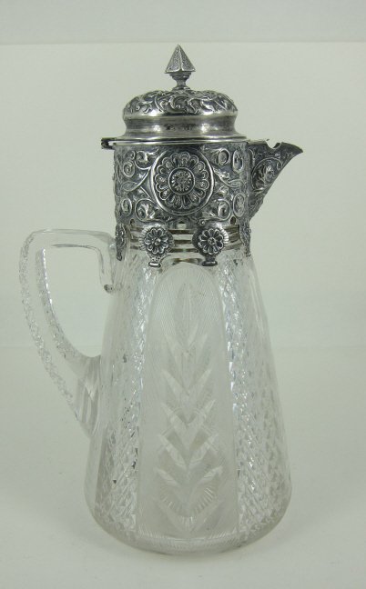 CONTINENTAL SILVER MOUNTED CRYSTAL CLARET JUG: The mounts with repousse foliate scrolled and rosette motif decoration. Cut crystal body with leafy panels. H. 11.25." Provenance: From the Fried Estate, Bedford NY Collectors for over 75 years.