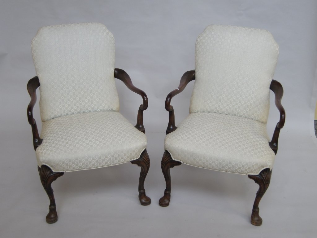 PAIR ARM CHAIRS: Pair of Antique George II style carved mahogany framed open arm chairs having shepherd crooked arms. The whole raised on curved legs, having shell carved knees terminating on slippered pad feet. Cream