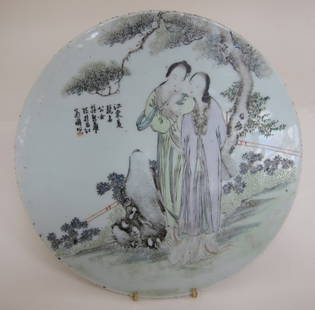 CHINESE PORCELAIN PLAQUE: An antique polychrome glazed circular plaque depicting two female figures, one holding a fan behind her in a flowering garden. Character marks upper left. Remains of a wax seal on verso. Diam. 11.5."