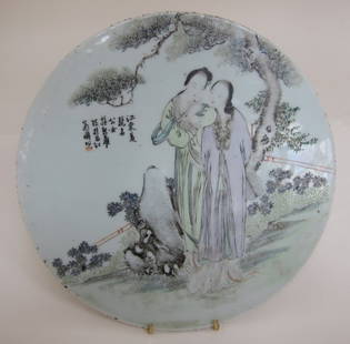 CHINESE PORCELAIN PLAQUE: An antique polychrome glazed circular plaque depicting two female figures, one holding a fan behind her in a flowering garden. Character marks upper left. Remains of a wax seal on verso. Diam. 11.5."