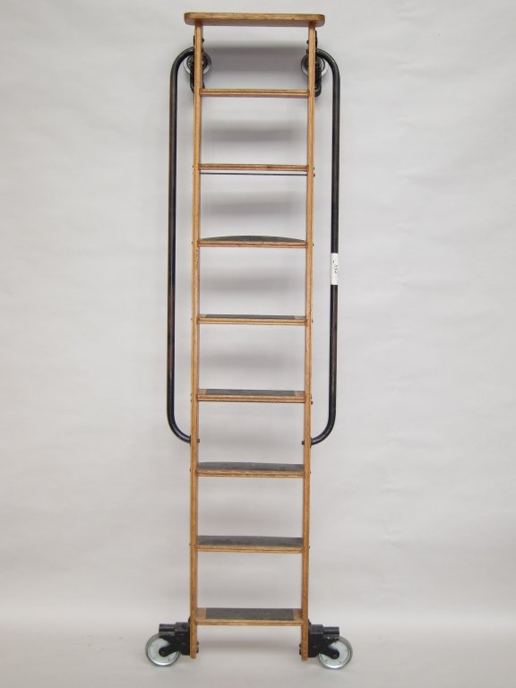 INDUSTRIAL LIBRARY LADDER: A solid oak constructed ladder with iron side handrails having 8 steps and wheel rollers. W. 16, H. 89.5."