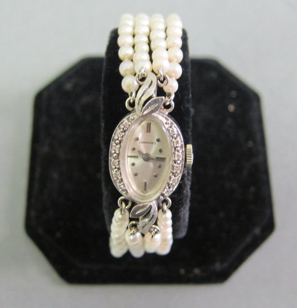 LONGINES LADY'S WRISTWATCH WITH DIAMONDS & PEARLS: 14k white gold stamped L & W. The oval face surrounded by small diamonds with a band of 4 strands of seed pearls, with a 14k white gold clasp.