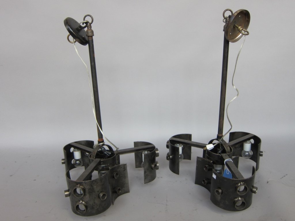 PAIR HANGING FIXTURES: A pair 20th Century Industrial design wrought metal hanging light fixtures. Each having four lights protected by pierced convex panels. Measures: 18"D, 31: H