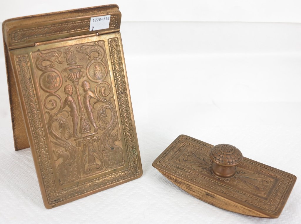 TIFFANY STUDIOS GILT BRONZE DESK SET: A hinged notebook cover and a roller blotter. Marked Tiffany Studios New York on the side of the roller. In a Renaissance revival pattern. Cover 7.5 x 4.5." Roller L. 5.5." Provenance: Property from a