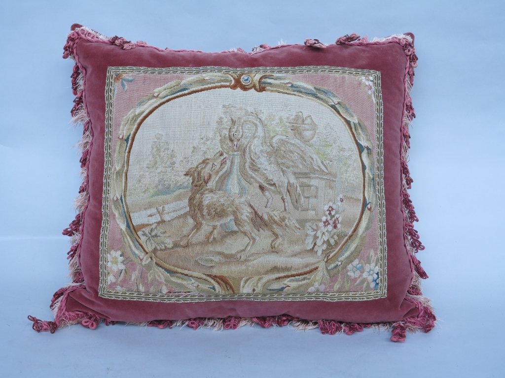 PILLOW: An antique French Aubusson tapestry paneled pink velvet and fringed pillow. Depicting a dog and swan in a garden landscape. Measures: 20" W. x 24" L. Pre-Sale Estimate: $ 200/300