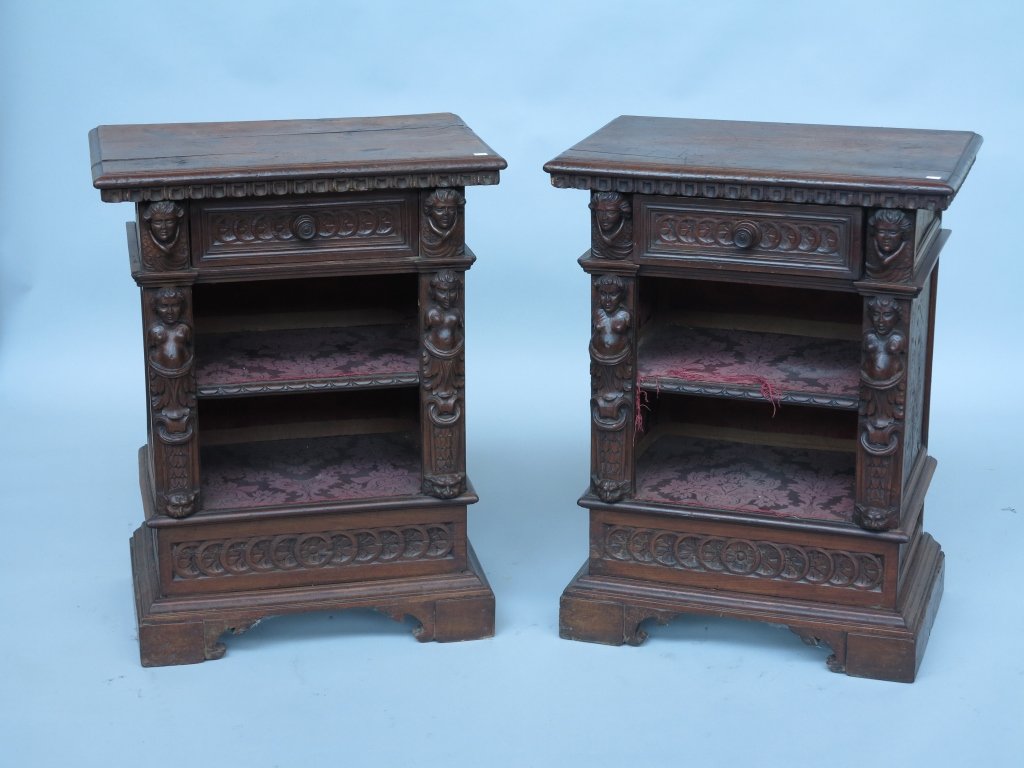 PAIR OF STANDS: A pair antique continental Renaissance revival heavily carved walnut stands. The beveled rectangular top above one short frieze drawer over two open shelf compartments centered by carved figural flush