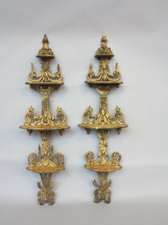 PAIR ANTIQUE TIERED WALL BRACKETS: Carved and gilt with acanthus scrolls and floral motifs with four graduated shaped shelves covered in gold velvet (worn). With a bow terminal. Some losses to decoration. Measures: H. 36" each